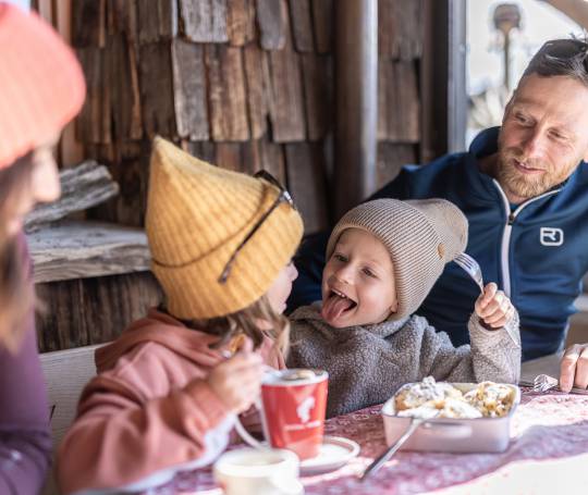 Familie isst Kaiserschmarn auf der Alm